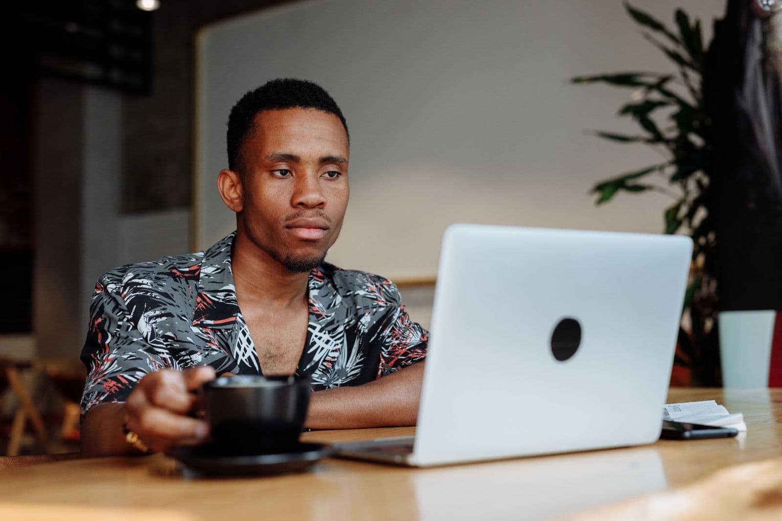 A business owner relaxing with a coffee while working on his laptop