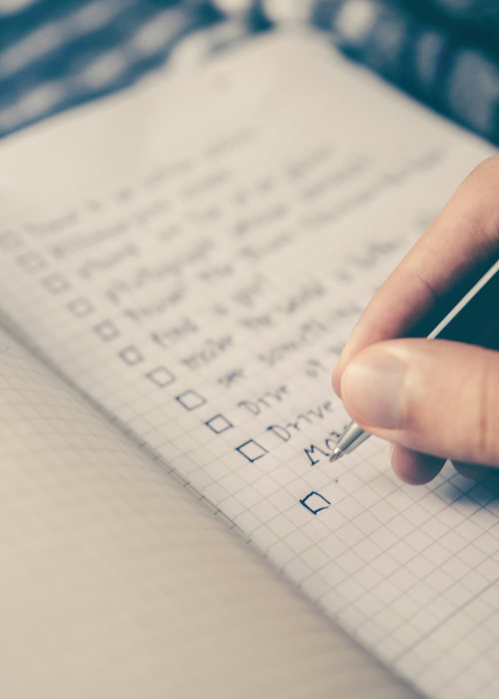 Hand writing a checklist in a notebook while setting up a business